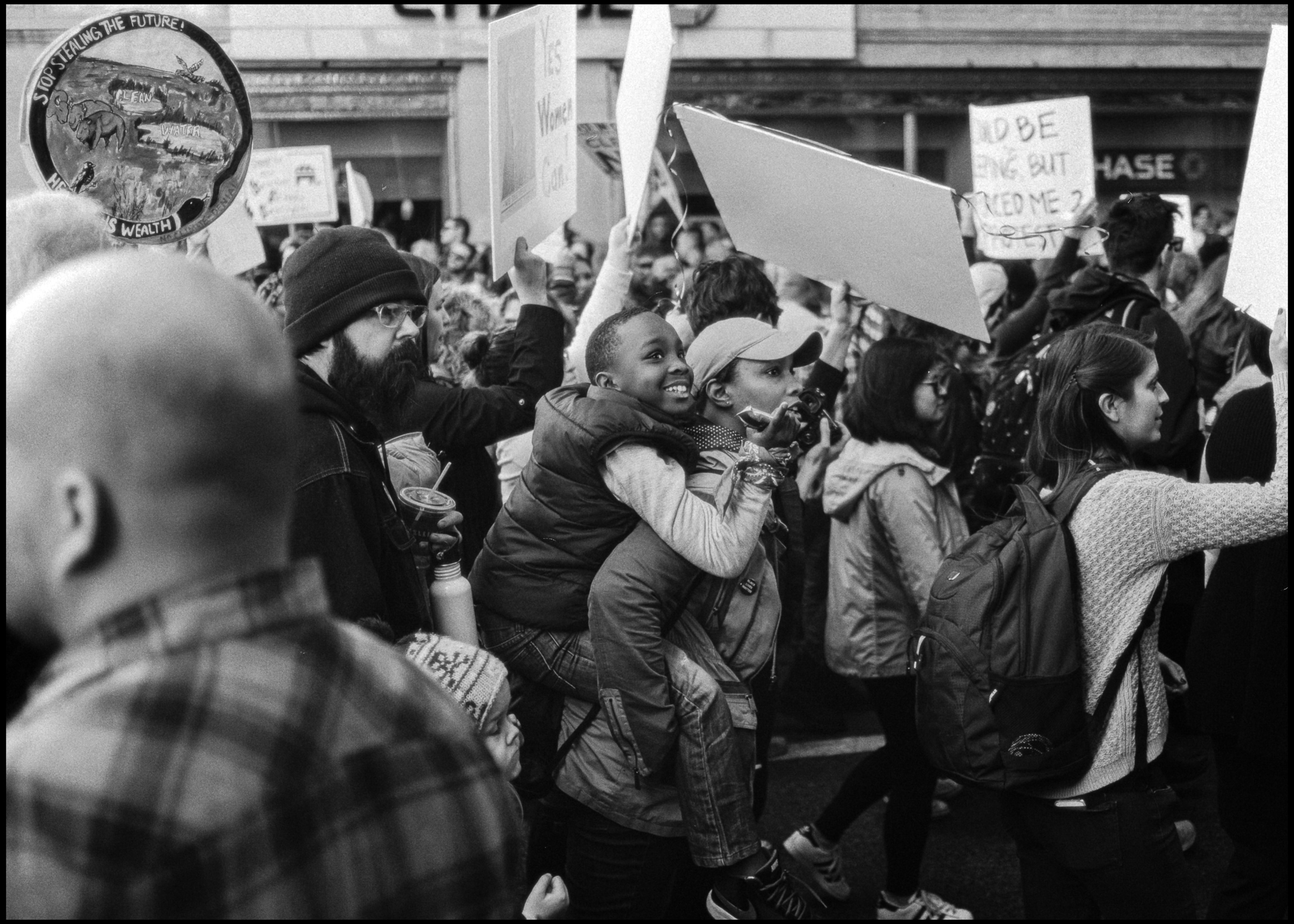 Kid on a mother's back in the march crowd, Chicago 2017